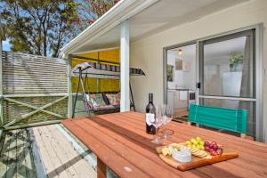 a wooden table with wine glasses and fruit on a patio at The Taranui Cottage - Mangawhai Heads Holiday Home in Mangawhai
