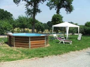 a large pool with a canopy and a chair and an umbrella at Au Beau Gîte in Carentoir