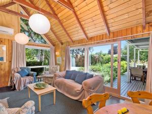 een woonkamer met een bank en een tafel bij Copper Beech Cottage - Wharewaka Holiday Home in Taupo