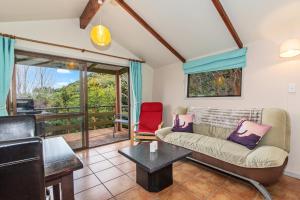a living room with a couch and a table at The Cowshed Wairoro Park - Russell Holiday Home in Russell