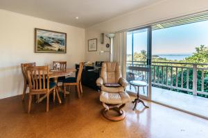 a living room with a table and a balcony at Hedgehog Heights - Waiheke Island in Surfdale