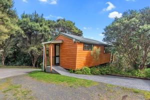 a small wooden house in the woods at The Cowshed Wairoro Park - Russell Holiday Home in Russell