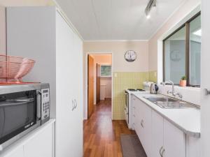 a kitchen with a sink and a microwave at Relax Lakeside - Lake Rotoiti Bach in Rotoiti