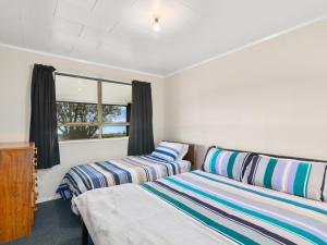 een slaapkamer met 2 bedden en een raam bij Relax Lakeside - Lake Rotoiti Bach in Rotoiti