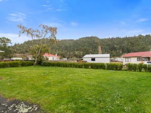 a yard with a green lawn with a tree and houses at Relax Lakeside - Lake Rotoiti Bach in Rotoiti