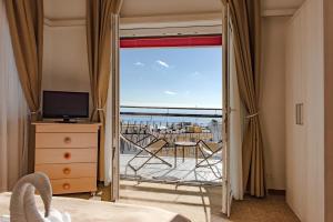 een slaapkamer met uitzicht op de oceaan vanaf een balkon bij Hotel Principe in Sanremo