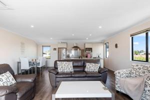 a living room with a couch and a table at Sparkling Ocean Views - Papamoa Holiday House in Papamoa
