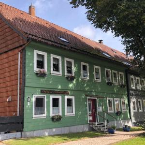 un edificio verde con ventanas blancas y techo rojo en Haus Hohensee, en Clausthal-Zellerfeld