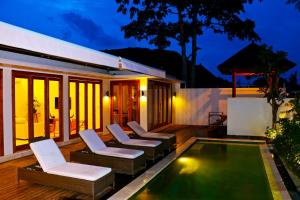 a patio with chairs and a swimming pool at night at Kokomo Resort Gili Gede in Gili Gede