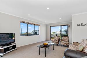 a living room with a couch and a tv at Sparkling Ocean Views - Papamoa Holiday House in Papamoa