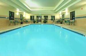 a swimming pool with chairs and tables in a building at Staybridge Suites Fayetteville, an IHG Hotel in Fayetteville