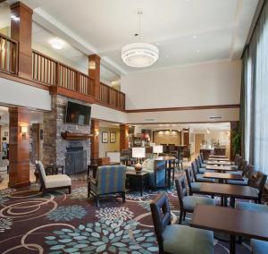 um átrio do hotel com mesas e cadeiras e uma lareira em Staybridge Suites Fayetteville, an IHG Hotel em Fayetteville