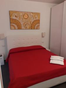 Un dormitorio con una cama roja con una pintura en la pared en Residence Villa Gori, en Rímini