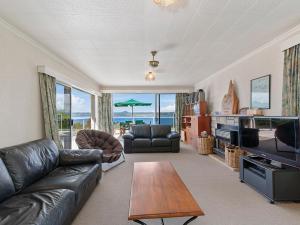 a living room with a leather couch and a table at Lofty Lakeviews - Acacia Bay Holiday Home in Taupo