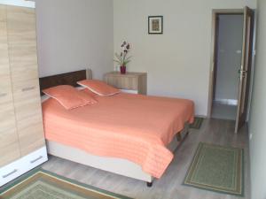 a bedroom with a bed with an orange comforter at Katica nyaraló in Balatonföldvár
