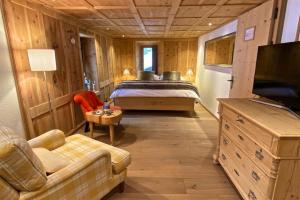 ein Schlafzimmer mit einem Bett, einem Sofa und einem TV in der Unterkunft Hotel Chesa Staila in La Punt-Chamues-ch