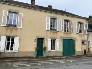 a building with green doors and windows on a street at Le Trianon in Le Bourgneuf-la-Forêt