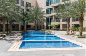 a swimming pool with palm trees in front of a building at BellaVista Burj Views Tower Opposite Dubai Mall in Dubai