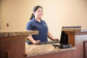 a woman standing at a desk with a laptop computer at Candlewood Suites Wake Forest-Raleigh Area, an IHG Hotel in Wake Forest