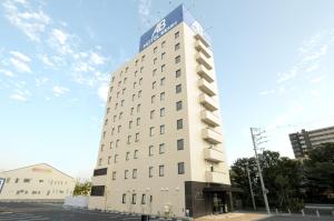 a tall white building with a blue sign on it at AB Hotel Tokai Otagawa in Tokai