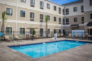 Staybridge Suites North Jacksonville, an IHG Hotel في جاكسونفيل: مسبح امام مبنى به طاولات وكراسي