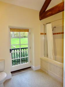 a bathroom with a shower and a toilet and a window at Glanhenwye Courtyard Cottages in Glasbury