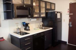 a kitchen with black cabinets and a black refrigerator at Candlewood Suites Youngstown W - I-80 Niles Area by IHG in Austintown