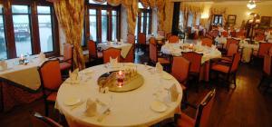 a dining room with white tables and chairs and windows at Gajner Palace-Heritage by HRH Group of Hotels in Gajner