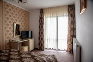 a bedroom with a bed and a television and a window at Pensiunea Eden in Ranca