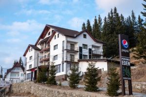 a large white building with a sign in front of it at Pensiunea Eden in Ranca