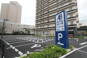 un estacionamiento con una señal de estacionamiento frente a un edificio en AB Hotel Omihachiman, en Omihachiman
