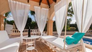 eine Veranda mit einer Schaukel, einem Tisch und Stühlen in der Unterkunft Villa Son Serra, Pool and Chill Out close to the beach in Son Serra de Marina