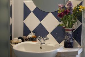 lavabo con jarrón de flores y espejo en Glanhenwye Courtyard Cottages en Glasbury