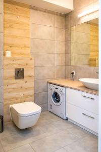 uma casa de banho com uma máquina de lavar roupa e um lavatório em Apartament Zatoka em Puck