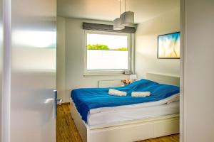 um quarto com uma cama com lençóis azuis e uma janela em Apartament Zatoka em Puck