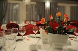 a table with wine glasses and a vase of orange flowers at Papillon in Piteşti
