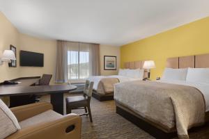 a hotel room with two beds and a desk at Candlewood Suites Vestal - Binghamton by IHG in Vestal