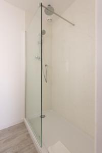uma cabina de duche em vidro numa casa de banho branca com piso em The St Enodoc Hotel em Wadebridge