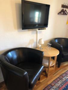 een woonkamer met 2 zwarte lederen stoelen en een tafel bij Glimminge Bed & Breakfast in Simrishamn