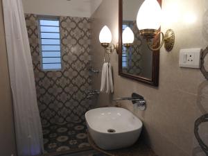 ein Bad mit einem Waschbecken und einem Spiegel in der Unterkunft Hotel Jai Niwas in Jaipur