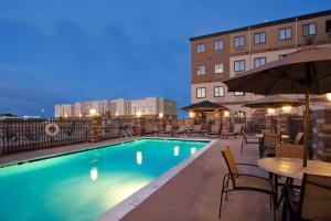 una piscina por la noche con mesas y sillas en Staybridge Suites - Odessa - Interstate HWY 20, an IHG Hotel, en Odessa