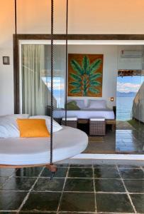 a swinging bed in a room with a view of the ocean at Casa da Ilha in Praia de Araçatiba