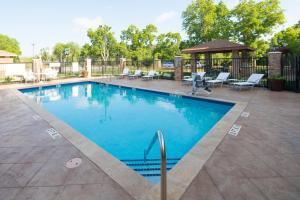 a swimming pool with chairs and a gazebo at Staybridge Suites - Lake Jackson by IHG in Lake Jackson
