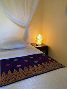 a bedroom with a bed and a lamp on a table at Kanda Homestay in Sidemen