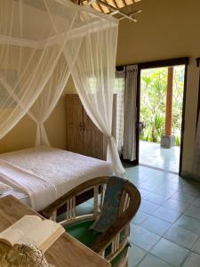 a bedroom with a bed with curtains and a table at Kanda Homestay in Sidemen