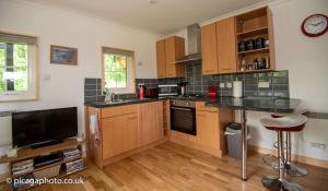 a kitchen with wooden cabinets and a counter top at Loch Ness Studio Blairbeg in Drumnadrochit