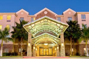 a building with palm trees in front of it at Staybridge Suites McAllen by IHG in McAllen