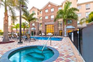 a swimming pool with chairs and a building at Staybridge Suites McAllen, an IHG Hotel in McAllen