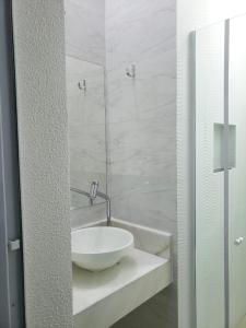 a bathroom with a white sink and a shower at Pousada Della Nonna in Presidente Prudente