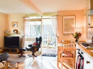 a kitchen with a living room with a chair and a table at River Cottage Hot tub spa in Drumnadrochit